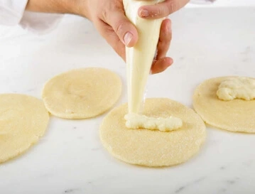 After filling and shaping your bichons, the final step before baking is arranging them on the tray. Take a baking tray and line it with parchment paper to prevent sticking and make cleanup a breeze.