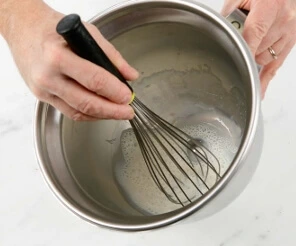 "Whisking fresh yeast into whole milk in a stand mixer bowl to start croissant dough.