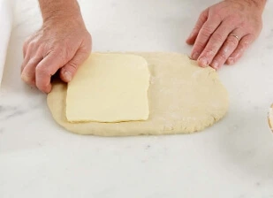 Flattening the croissant dough after proofing and preparing the laminated butter square.