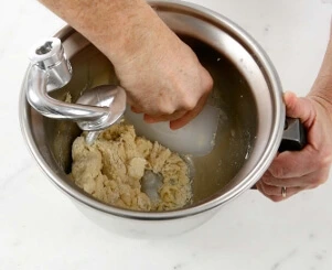 "Adding ingredients to the stand mixer and kneading the croissant dough until smooth and elastic.