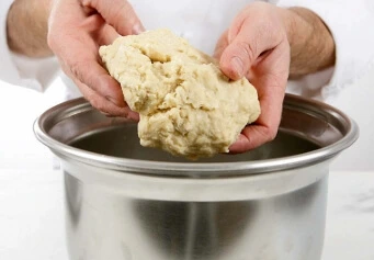 Croissant dough shaped into a ball and covered with plastic wrap for the first proofing.
