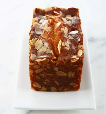 Freshly baked fruitcake being brushed with syrup and rum for a shiny, flavorful finish.