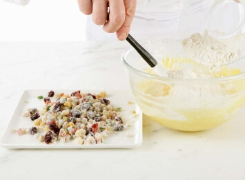 Sifting flour and baking powder together before folding them into the fruitcake batter for a smooth and fluffy texture.