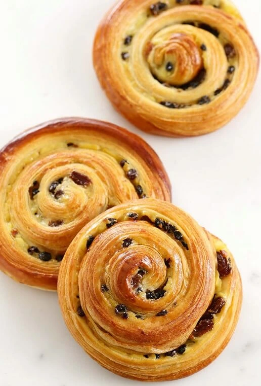 Raisin buns baking in the oven, turning golden brown, and filling the kitchen with a delightful aroma.