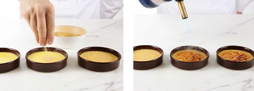 A hand holding a blowtorch caramelizing sugar on a crème brûlée, with the surface turning golden and glossy.
