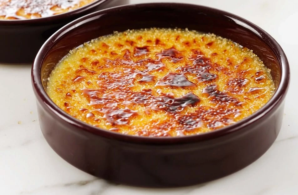 Crème brûlées cooling in the refrigerator after being caramelized, each with a golden crust and chilled ramekin.