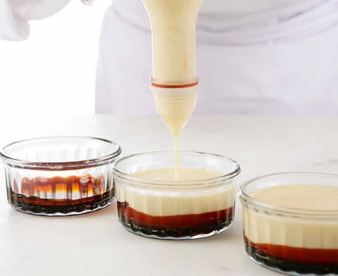Un plat de dessert cuit au bain-marie dans un four, avec de la vapeur créant un environnement de cuisson doux.