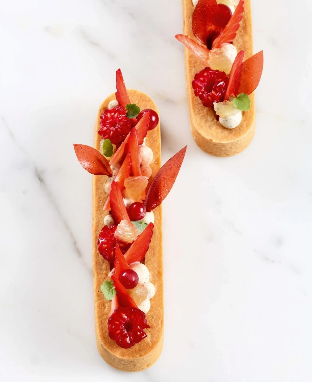 Tarte aux fruits rouges élégamment décorée avec crème mousseuse, gelée de fruits et feuilles de fruits rouges, réalisée selon la recette de Nina Métayer.