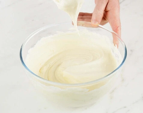 Whisking egg yolks as hot sugar syrup is poured to create pâte à bombe