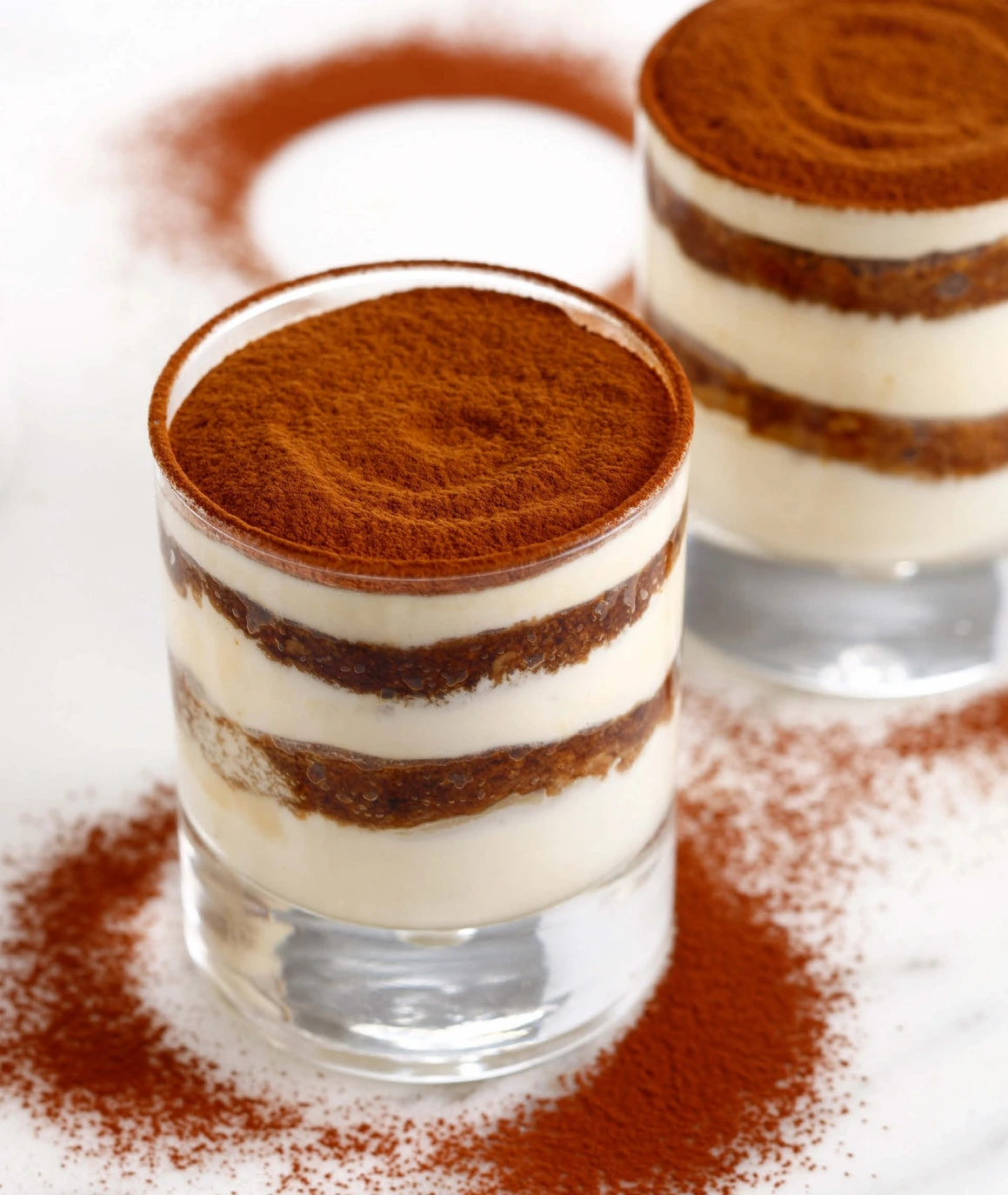 Elegant individual tiramisu desserts layered in clear verrines with cocoa-dusted tops