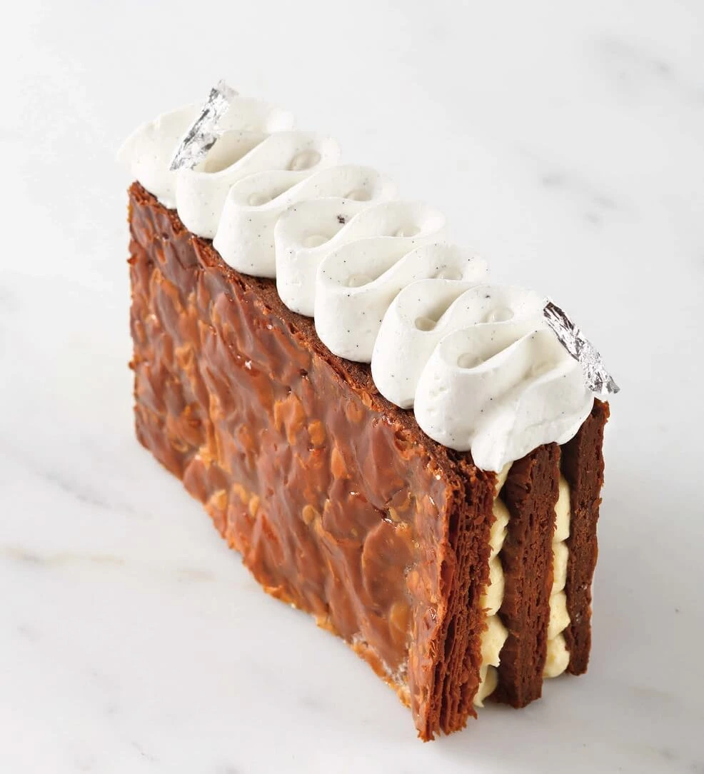 Chocolate Millefeuille dessert with three layers of golden puff pastry, filled with vanilla mousseline cream and topped with piped vanilla Chantilly.