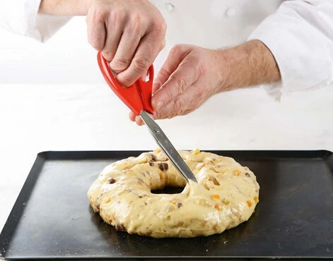 Pastry brush gently applying egg wash over the surface of a proofed Kougelhopf dough in its traditional fluted mold.