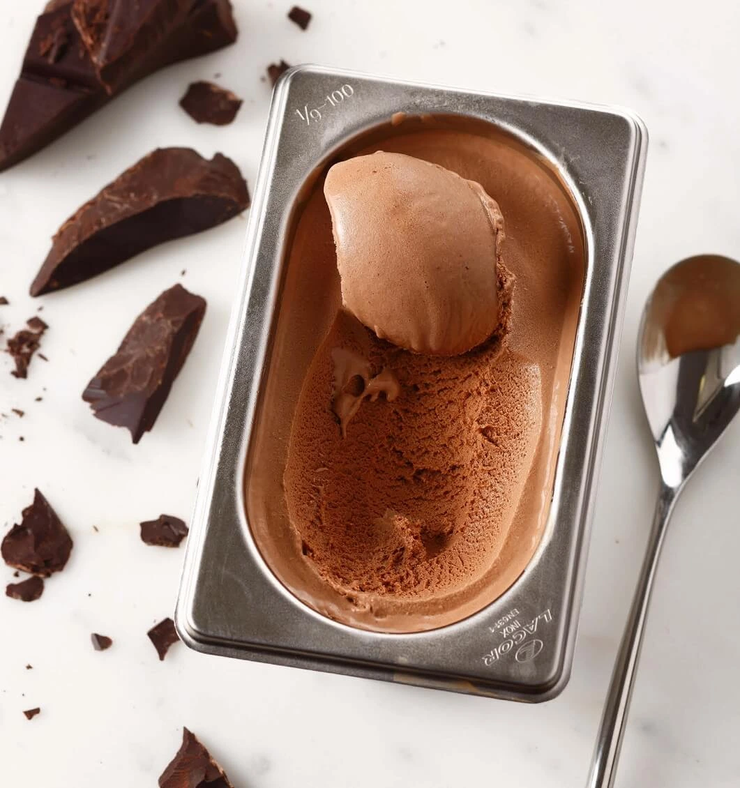 Homemade chocolate ice cream in a rustic ceramic bowl with a silver spoon.