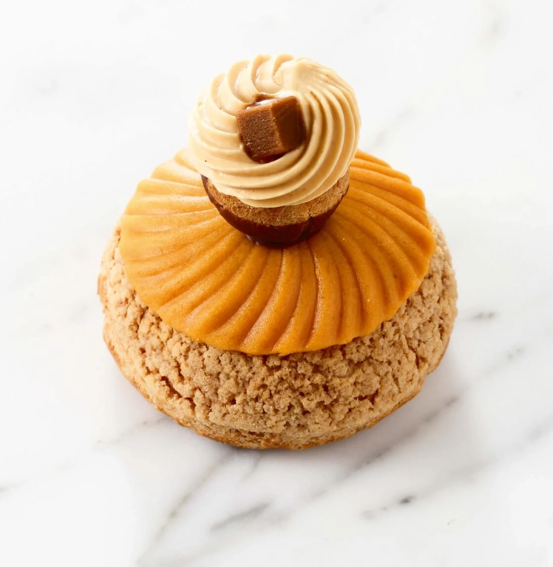 Caramel religieuses with glossy caramel glaze and delicate almond paste decorations on a white plate.