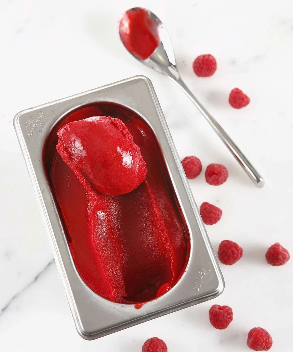 Full-fruit raspberry sorbet served in a chilled bowl, garnished with fresh raspberries and mint leaves