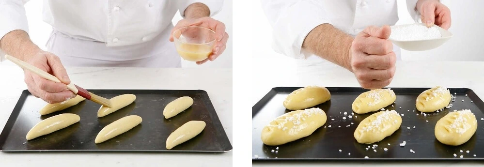 Applying an egg wash to milk bread dough balls before baking.