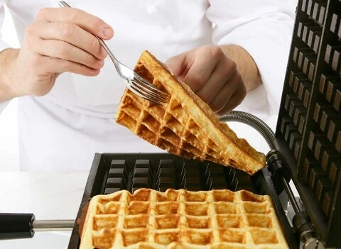 Golden, crispy waffles cooking to perfection, with chef-approved tips for the ultimate texture.