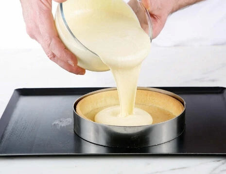 Assembling and baking the cheesecake, with a golden-brown top and smooth surface.