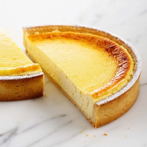 Golden-brown baked cheesecake fresh out of the oven, with a smooth, slightly risen surface.
