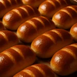 Pain au lait maison, doré et moelleux, posé sur une nappe avec un léger saupoudrage de farine