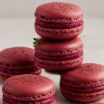 Close-up view of gourmet savory beetroot macarons with a vibrant pink hue and creamy filling, elegantly plated for an appetizer.