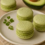 Close-up of savory avocado macarons with vibrant green filling, delicately assembled on a white plate for gourmet presentation.