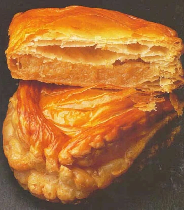 Golden-brown cherry and chestnut turnovers with flaky puff pastry on a rustic wooden board