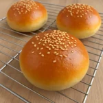 Homemade hamburger buns with golden crust on a wooden table